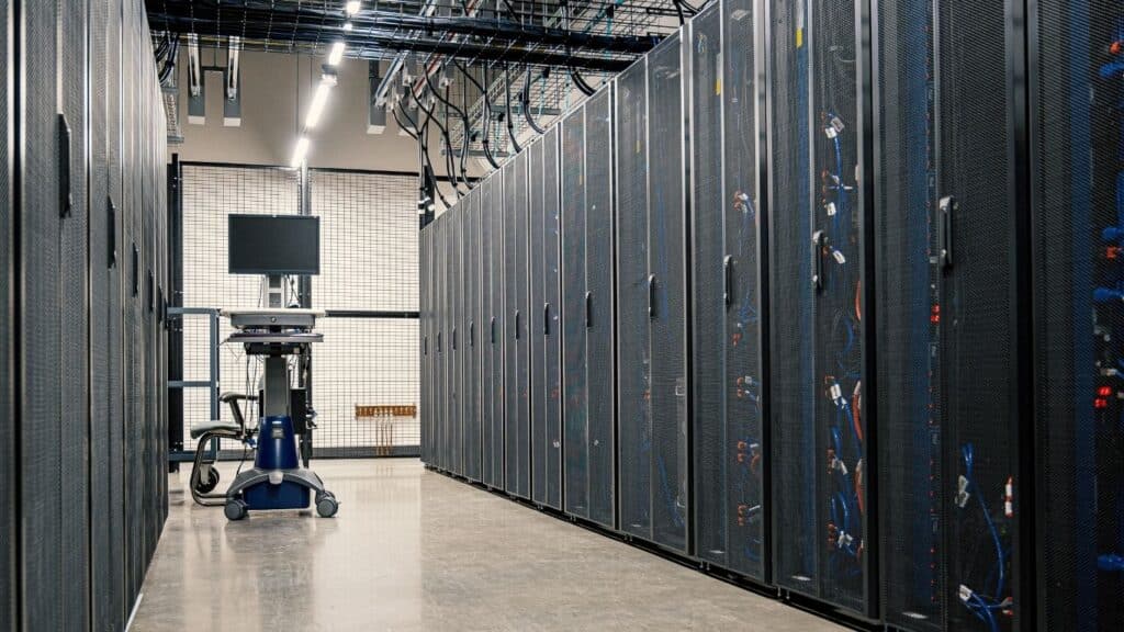 Data center corridor with server racks and monitoring equipment, illustrating cloud infrastructure for utilities and operational efficiency.