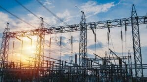 Electricity substation with high-voltage transmission lines against a sunset sky, illustrating modern utility infrastructure and energy solutions.